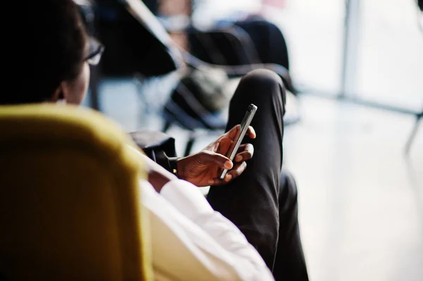 Business african american man wear on white shirt, tie and glasses at office, sitting on chair and holding mobile phone.