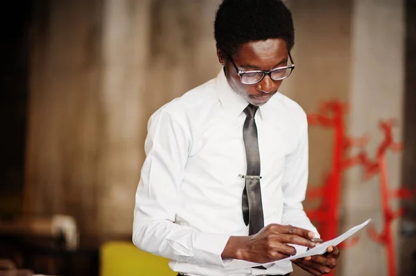 Business african american man wear on white shirt, tie and glasses at office, holding papers on hand and write something.