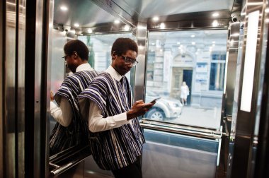 Geleneksel giysiler ve gözlük cep telefonu reçine veya modern Asansör ile Afrika adam.