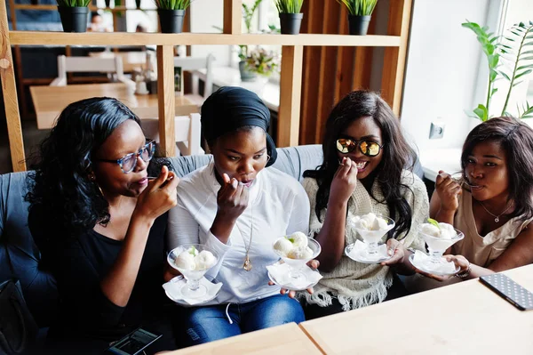 Kafede masada oturan ve buz yeme dört Afro-Amerikan kız tatlı krem.