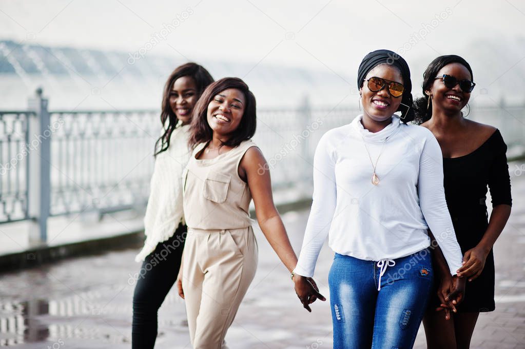 Group of four african american girls having fun against lake with fountains.