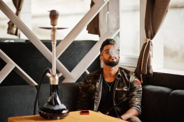 Arap adam gözlük ve askeri ceket sigara nargile sokak barında şık sakal. Geri kalan Arap modelinde.