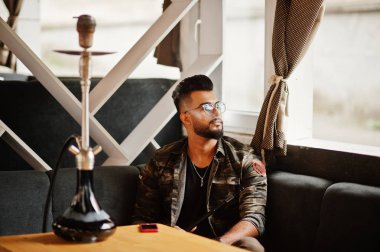 Arap adam gözlük ve askeri ceket sigara nargile sokak barında şık sakal. Geri kalan Arap modelinde.