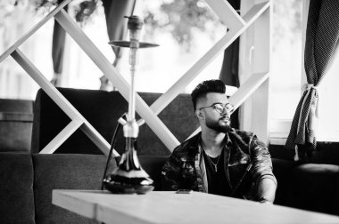 Arap adam gözlük ve askeri ceket sigara nargile sokak barında şık sakal. Geri kalan Arap modelinde.