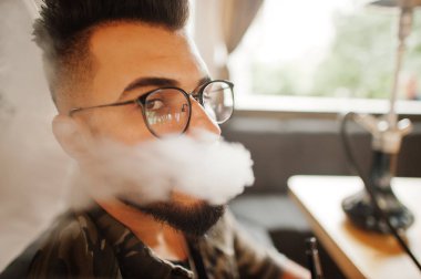 Gözlük ve duman sigara nargile sokak barda ile askeri ceket şık sakal Arap insan kafası kapatın. Geri kalan Arap modelinde.