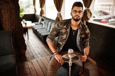 Arap adam gözlük ve askeri ceket sigara nargile sokak barında şık sakal. Geri kalan Arap modelinde.
