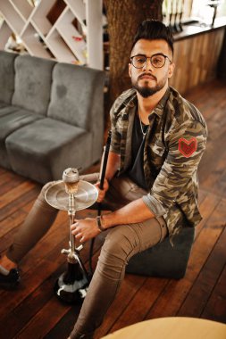 Arap adam gözlük ve askeri ceket sigara nargile sokak barında şık sakal. Geri kalan Arap modelinde.