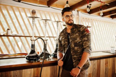 Arap adam gözlük ve askeri ceket sigara nargile sokak barında şık sakal. Geri kalan Arap modelinde.