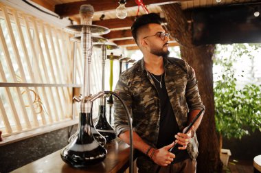 Arap adam gözlük ve askeri ceket sigara nargile sokak barında şık sakal. Geri kalan Arap modelinde.