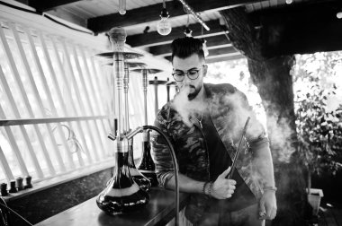 Arap adam gözlük ve askeri ceket sigara nargile sokak barında şık sakal. Geri kalan Arap modelinde.