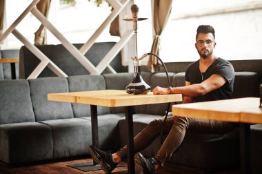 Arap adam gözlük ve siyah t-shirt sigara nargile sokak barında şık sakal. Geri kalan Arap modelinde.
