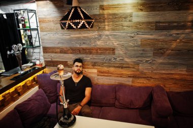 Arap adam gözlük ve siyah tişört sigara nargile bar kapalı şık sakal. Geri kalan Arap modelinde.