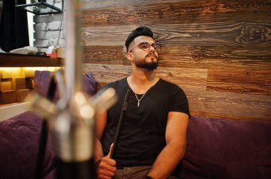 Arap adam gözlük ve siyah tişört sigara nargile bar kapalı şık sakal. Geri kalan Arap modelinde.