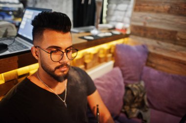 Arap adam gözlük ve siyah tişört sigara nargile bar kapalı şık sakal. Geri kalan Arap modelinde.
