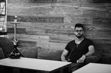 Arap adam gözlük ve siyah tişört sigara nargile bar kapalı şık sakal. Geri kalan Arap modelinde.
