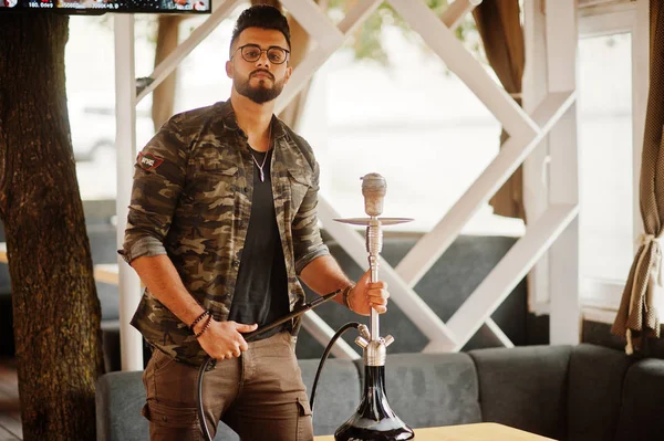 Arap adam gözlük ve askeri ceket sigara nargile sokak barında şık sakal. Geri kalan Arap modelinde.