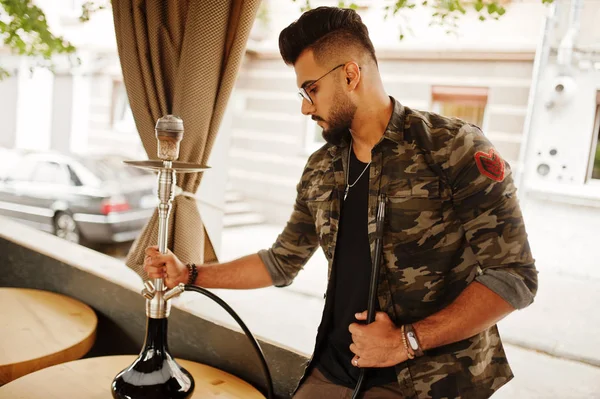 Arap adam gözlük ve askeri ceket sigara nargile sokak barında şık sakal. Geri kalan Arap modelinde.
