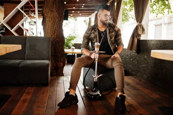Arap adam gözlük ve askeri ceket sigara nargile sokak barında şık sakal. Geri kalan Arap modelinde.