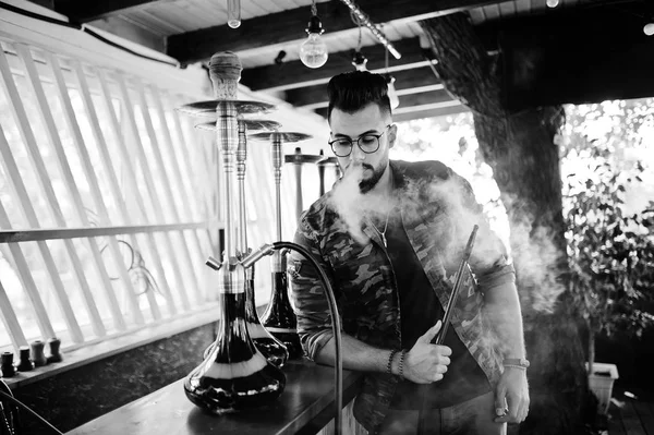 Arap adam gözlük ve askeri ceket sigara nargile sokak barında şık sakal. Geri kalan Arap modelinde.