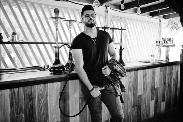 Arap adam gözlük ve siyah t-shirt sigara nargile sokak barında şık sakal. Geri kalan Arap modelinde.