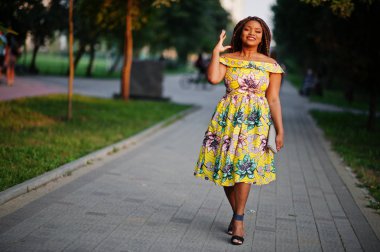 Sevimli küçük yükseklik Afro-Amerikan Kız dreadlocks, günbatımında poz renkli sarı elbise giymek.