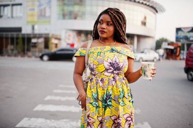 Sevimli küçük yükseklik dreadlocks, Afrikalı-Amerikalı kızla giymek renkli sarı elbise, Ticaret Merkezi ile kahve el altında karşı yaya geçidi, yürüyüş.