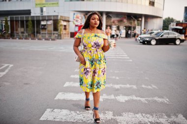 Sevimli küçük yükseklik dreadlocks, Afrikalı-Amerikalı kızla giymek renkli sarı elbise, Ticaret Merkezi ile kahve el altında karşı yaya geçidi, yürüyüş.