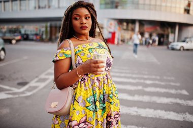 Sevimli küçük yükseklik dreadlocks, Afrikalı-Amerikalı kızla giymek renkli sarı elbise, Ticaret Merkezi ile kahve el altında karşı yaya geçidi, yürüyüş.