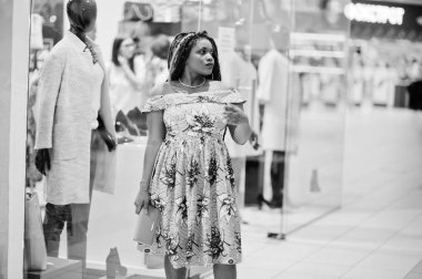 Sevimli küçük yükseklik Afro-Amerikan Kız dreadlocks, vitrin manken ile karşı Alışveriş Merkezi'nde renkli sarı elbise giymek. Siyah ve beyaz.