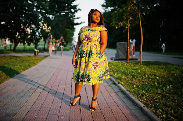 Sevimli küçük yükseklik Afro-Amerikan Kız dreadlocks, günbatımında poz renkli sarı elbise giymek.