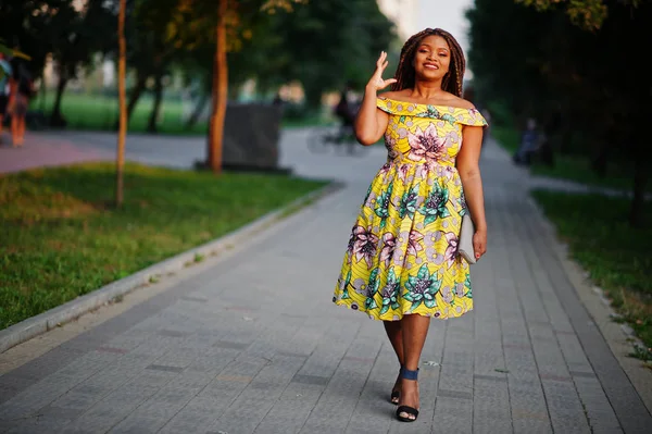 Sevimli küçük yükseklik Afro-Amerikan Kız dreadlocks, günbatımında poz renkli sarı elbise giymek.