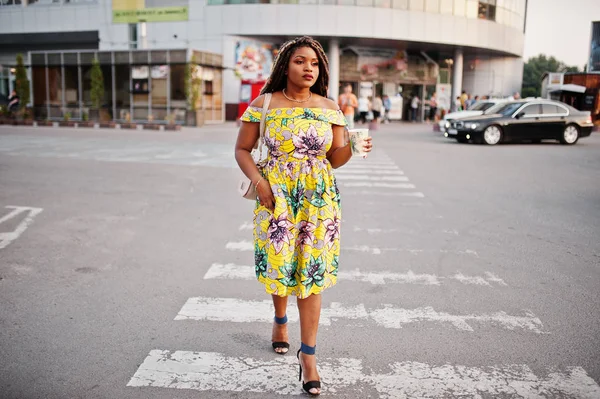 Sevimli küçük yükseklik dreadlocks, Afrikalı-Amerikalı kızla giymek renkli sarı elbise, Ticaret Merkezi ile kahve el altında karşı yaya geçidi, yürüyüş.