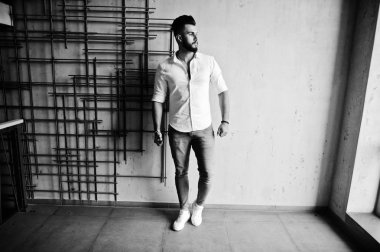 Şık uzun Arap adam modelinde beyaz gömlek, kot çelik duvara kapalı poz verdi. Sakal çekici Arap adam.