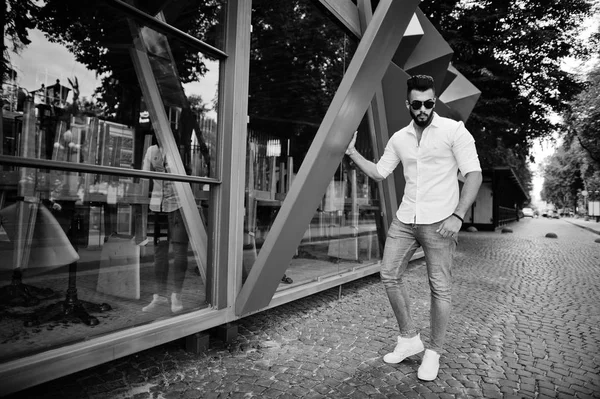 时尚高大的阿拉伯男子模特在白色衬衫 牛仔裤和太阳镜摆在城市的街道 胡子迷人的阿拉伯家伙 — 图库照片