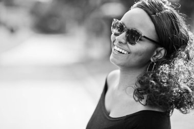 Güneş gözlüğü, gülümseyen Afro-Amerikan Kız portresi yakın siyah giysiler açık poz verdi. Şık siyah kadın.