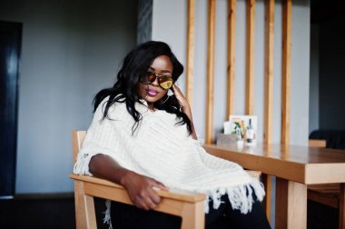 Güneş gözlüğü şık Afro-Amerikan Kız modern café'de poz verdi..