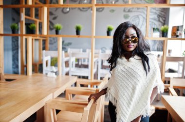 Güneş gözlüğü şık Afro-Amerikan Kız modern café'de poz verdi..