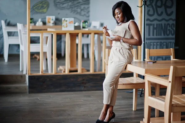 African american girl posed at cafe and eating ice cream.