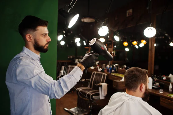 英俊的胡子人在理发店 理发师在工作 使用吹风机 — 图库照片