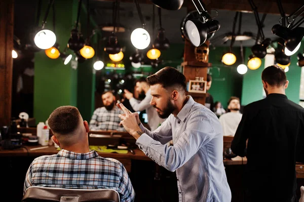 英俊的胡子男子在理发店 理发师在工作 在他的手机上拍照片 — 图库照片