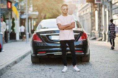 Güneş gözlüğü ve lüks otomobil karşı pembe tişört şık Hint sakallı adam. Hindistan zengin model şehrin sokaklarında, açık poz verdi.