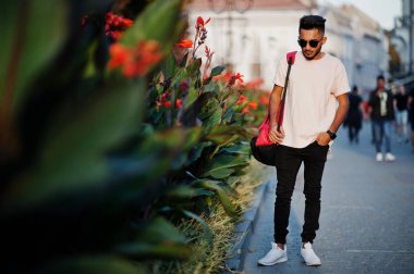Pembe tişört, güneş gözlüğü ve sırt çantası şık Hint sakallı adam. Hindistan modeli günbatımı şehrin sokaklarında, açık poz verdi.