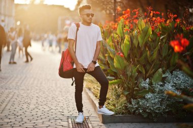 Pembe tişört, güneş gözlüğü ve sırt çantası şık Hint sakallı adam. Hindistan modeli günbatımı şehrin sokaklarında, açık poz verdi.