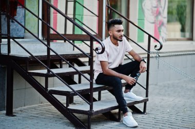 Pembe tişört şık Hint sakallı adam. Şehrin sokaklarında açık merdivenlerde oturan Hindistan modeli.