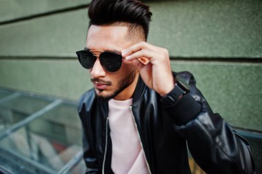 Siyah deri ceket ve güneş gözlükleri şık Hint sakallı adam. Hindistan modeli şehrin sokaklarında, açık poz verdi.