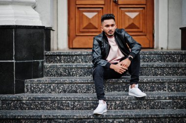 Siyah deri ceket şık Hint sakallı adam. Şehrin sokaklarında oturmuş poz Hindistan modeli.