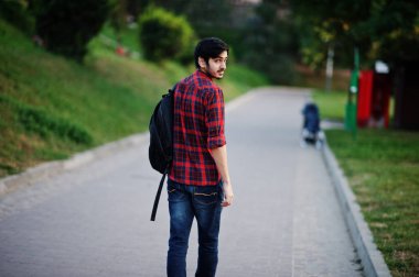 Genç Hintli öğrenci adam kırmızı kareli gömlek ve sırt çantası ile kot Sokağı'nda poz verdi..