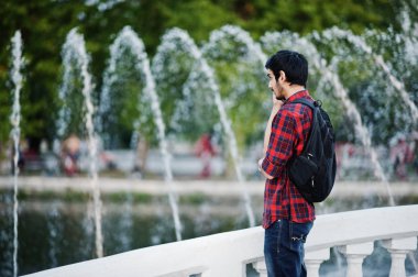 Akşam şehre çeşmeler karşı üzerinde kareli gömlek ve sırt çantası ile kot Genç Hintli öğrenci adama poz.