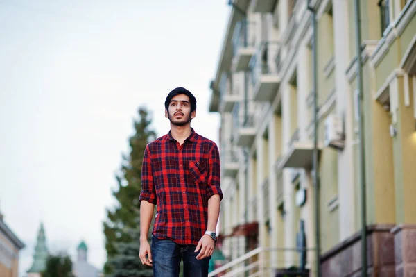 Young indian student man at red checkered shirt and jeans walking at city.