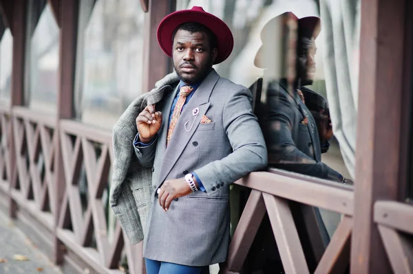 グレーのコート ジャケット ネクタイ 赤い帽子でスタイリッシュなアフリカ系アメリカ人モデル木製カフェに対して提起 — ストック写真